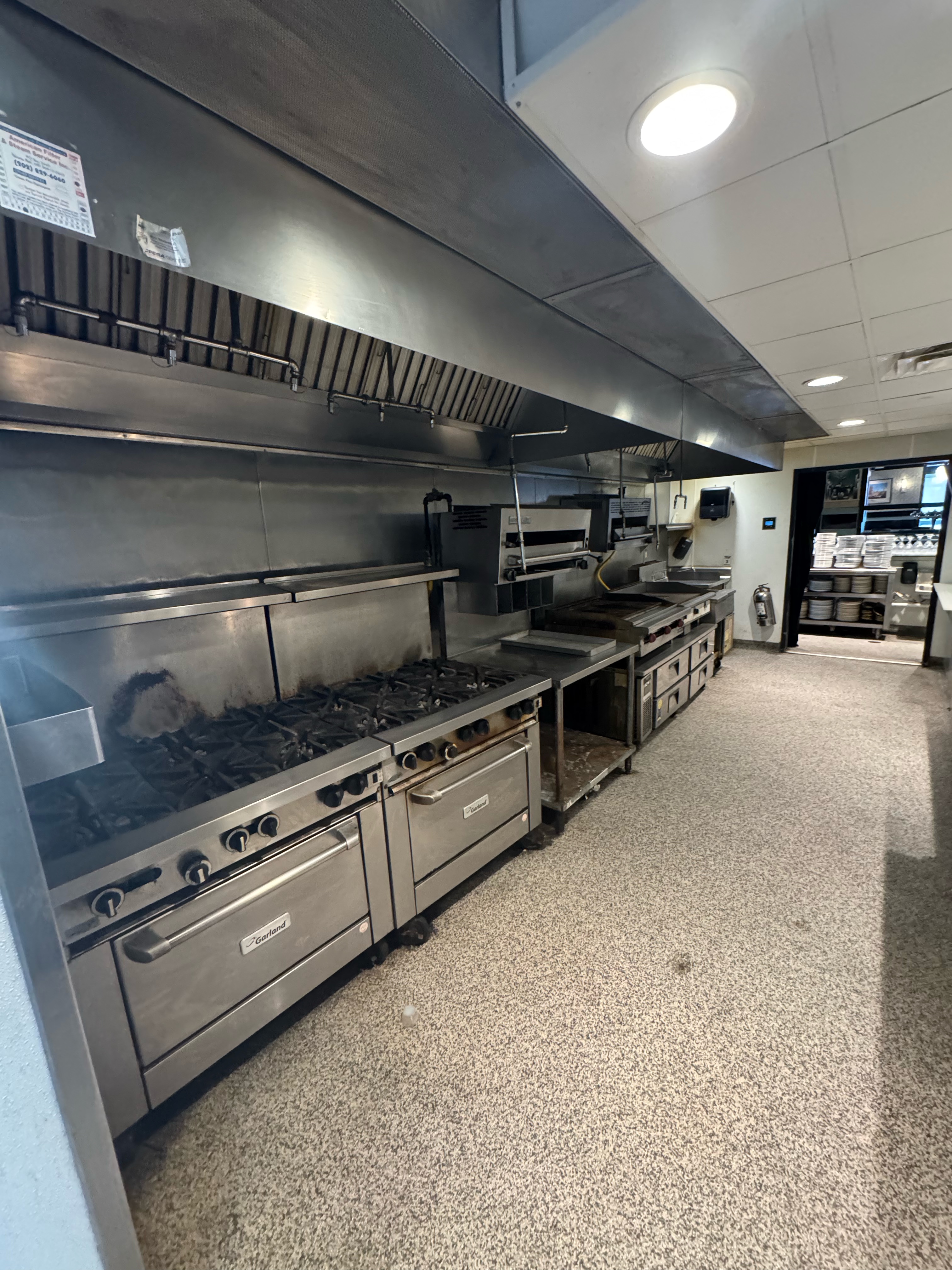 Finished commercial cook line with stainless ranges and hood — NLI install